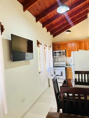 a kitchen with a table and a tv on the wall at Brisas de Valle in Jarabacoa