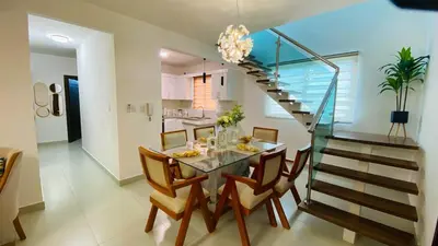 a dining room with a glass table and a staircase at Modern Rooftop Penthouse Private Large Jacuzzi for 12 in Santiago de los Caballeros