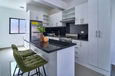 a kitchen with white cabinets and a black counter at Cozy Nest in La Romana