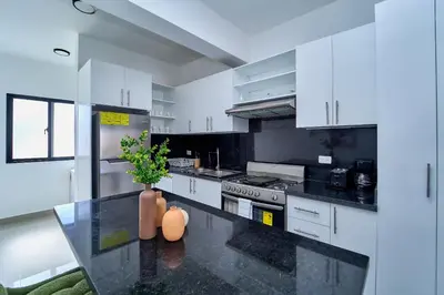 a kitchen with white cabinets and a black counter top at Cozy Nest in La Romana