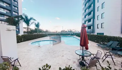 a swimming pool with chairs and a red umbrella at Livera park in Santiago de los Caballeros