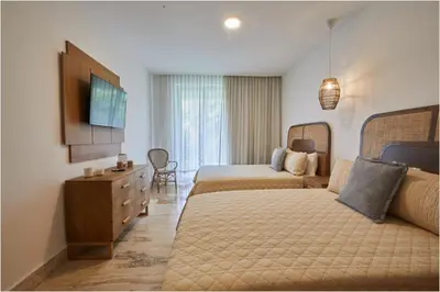 a hotel room with two beds and a television at Apartamento Moderno en Playa Dorada Piscina & Playa in Puerto Plata