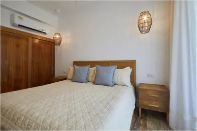 a bedroom with a large bed with blue pillows at Apartamento Moderno en Playa Dorada Piscina & Playa in Puerto Plata