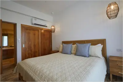 a bedroom with a large bed with blue pillows at Apartamento Moderno en Playa Dorada Piscina & Playa in Puerto Plata