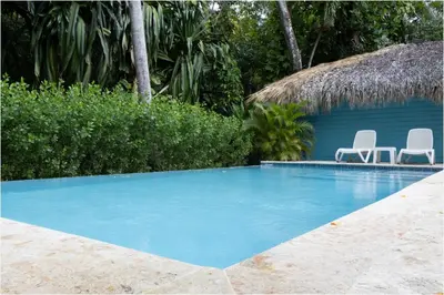a swimming pool with two chairs and a house at Apartamento Moderno en Playa Dorada Piscina & Playa in Puerto Plata