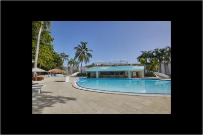 a large swimming pool with a building in the background at Apartamento Moderno en Playa Dorada Piscina & Playa in Puerto Plata