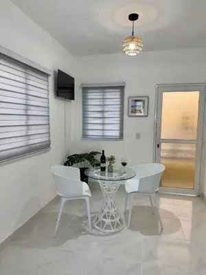 a dining room with a glass table and white chairs at Apartamento acogedor con cocina y balcón privado in Bayahibe