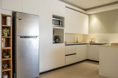 a kitchen with white cabinets and a stainless steel refrigerator at Beach Pool Jacuzzi Wifi Netflix Gym 5 Guests in Villas del Mar