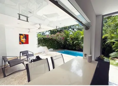 a dining room with a table and chairs and a pool at Tropical VILLAGE in Las Terrenas