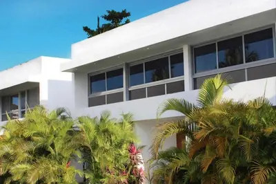 a white building with palm trees in front of it at Tropical VILLAGE in Las Terrenas
