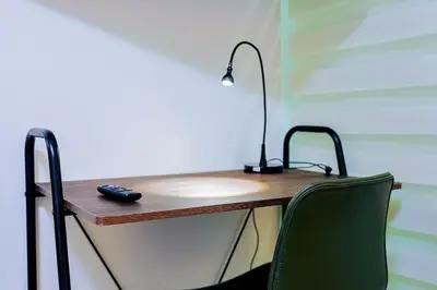 a desk with a lamp and a green chair at Cozy 2BR Condo, Spectacular Rooftop in Santo Domingo