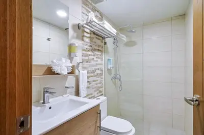 a white bathroom with a sink and a toilet at Comfy 2BR Condo, Roof Top Pool. in Santo Domingo