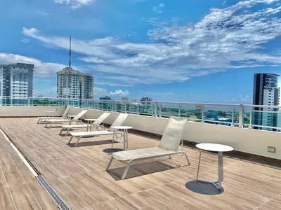 a row of chairs and tables on the roof of a building at Comfy 2BR Condo, Roof Top Pool. in Santo Domingo