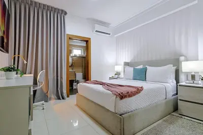 a bedroom with a bed and a table and a window at Comfy 2BR Condo, Roof Top Pool. in Santo Domingo