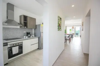 a white kitchen with a stove and a dining room at New Apartment! Beach getaway at Hard Rock in Punta Cana