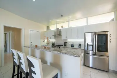 a kitchen with white cabinets and a counter with chairs at AC in Living Room, Infinity, Pool Luxury in Sosúa