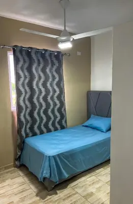 a bedroom with a bed with blue sheets and a window at Ocean Vibes - Bayahibe in Bayahibe