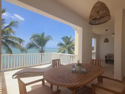 a dining room with a table and a balcony with the ocean at Cabarete Beach Palace 3-BDR Condo in Cabarete