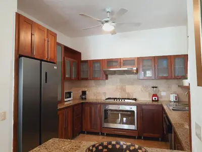 a kitchen with wooden cabinets and a stainless steel refrigerator at Cabarete Beach Palace 3-BDR Condo in Cabarete