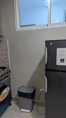 a kitchen with a black refrigerator and a trash can at Mitaly apartamentos RD H in Santo Domingo