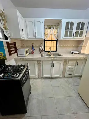 a kitchen with white cabinets and a sink and a stove at Apartamento in Boca Chica