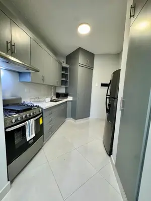 a kitchen with gray cabinets and a black refrigerator at Your ideal escape in Puerto Plata Beach and fun in San Felipe de Puerto Plata