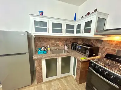 a kitchen with white cabinets and a sink and a refrigerator at Mi Refugio Apartment in Río San Juan