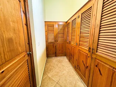 a hallway with wooden closet doors and a tiled floor at Residencial Hispaniola2 MastersMaidPoolBBQ in Sosúa