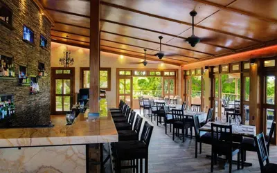 a restaurant with a bar and tables and chairs at Residencial Hispaniola2 MastersMaidPoolBBQ in Sosúa