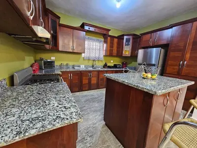 a large kitchen with wooden cabinets and granite counter tops at Magnificent accommodation in Puerto Plata