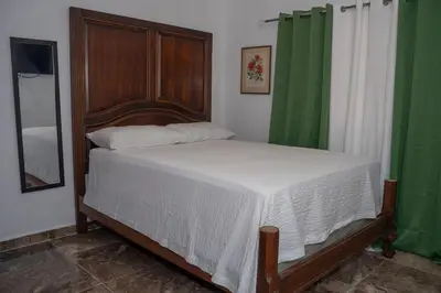 a bedroom with a bed with a wooden headboard and green curtains at Magnificent accommodation in Puerto Plata