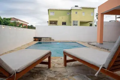 a swimming pool with two benches and a building at Magnificent accommodation in Puerto Plata