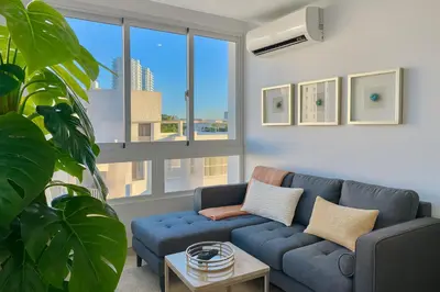 a living room with a blue couch and a large window at Cozy, City Center Condo in Santo Domingo