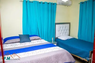 a bedroom with two beds and blue curtains at Villa en Pedernales in Pedernales
