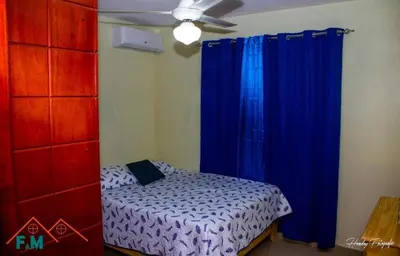 a bedroom with a bed with blue curtains and a ceiling fan at Villa en Pedernales in Pedernales
