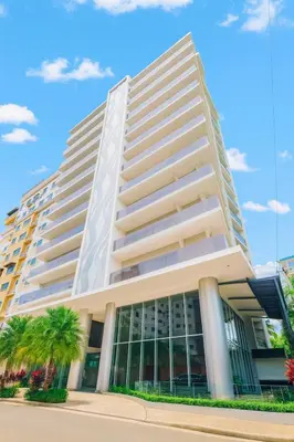 a large white building with palm trees in front of it at Comfy 1BR Apt, King Bed, Pool in Santo Domingo