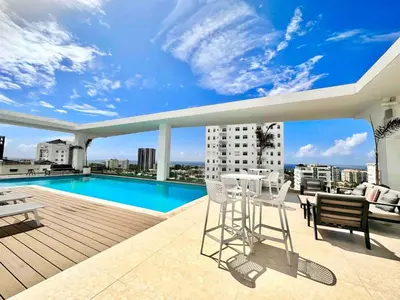 a balcony with a table and chairs and a swimming pool at Comfy 1BR Apt, King Bed, Pool in Santo Domingo