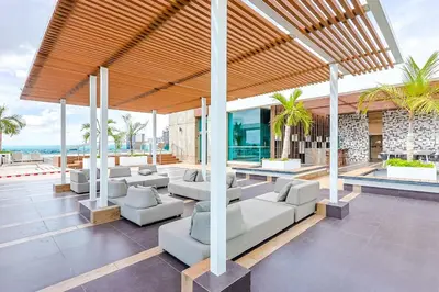 an outdoor patio with white couches and palm trees at Cozy City-Center 1BD Condo, Pool in Santo Domingo