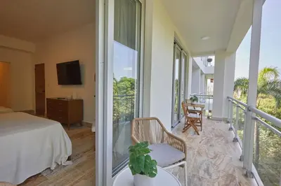 a bedroom with a balcony with a bed and a tv at Modern Escape with Pool & Beach in Puerto Plata