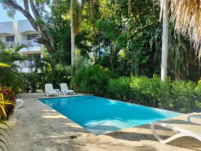 a swimming pool in a yard with chairs and trees at Modern Escape with Pool & Beach in Puerto Plata