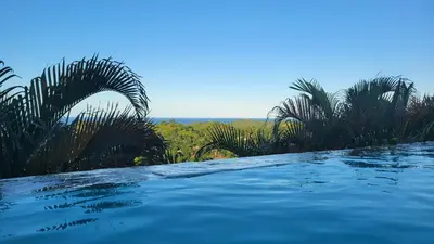 a swimming pool with palm trees and the ocean at Casa Las Piedras in Las Terrenas