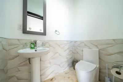 a bathroom with a sink and a toilet and a mirror at Luxury Villa, Pool & Prime Location in Sosúa