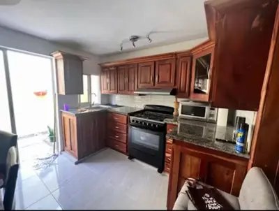 a kitchen with wooden cabinets and a stove top oven at Casa colinas del viento in Jacagua