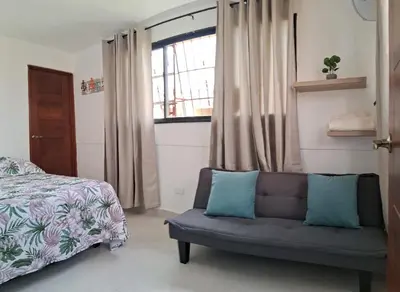 a bedroom with a couch and a bed and a window at Apartamento Las Carreras in Santo Domingo