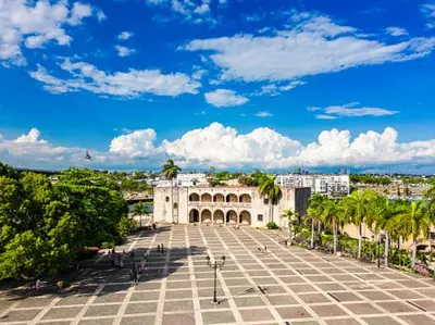 a large white building with palm trees and a blue sky at Apartamento Las Carreras in Santo Domingo