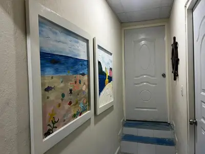 a hallway with two paintings on the wall and a white door at Villa Del Risco - House on the Beach in Boca Chica
