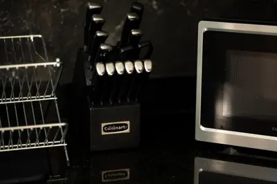 a group of knives in a knife block next to a microwave at Luxurious Apartment with pool near airport in Santiago de los Caballeros