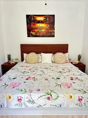 a bed with a floral comforter with two pillows at Apartman Tamarindo in La Laguna