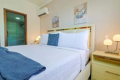 a bedroom with a large white bed with blue pillows at Comfy 1BR Centric Apt King Bed in Santo Domingo