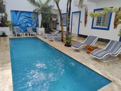 a swimming pool with lounge chairs in front of a building at Brisa de Alma Guesthouse in Bayahibe